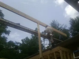 Carpenter setting a ridge beam over a new addition frame — Ice Dam Removal by Roofing Brothers in Bonaparte