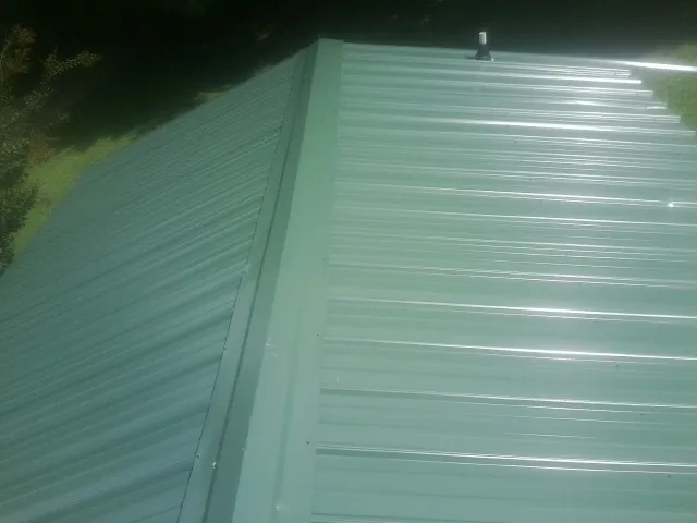 New green metal panels meeting at the ridge of a roof — Flat Roof Repair work by our crew in Bonaparte