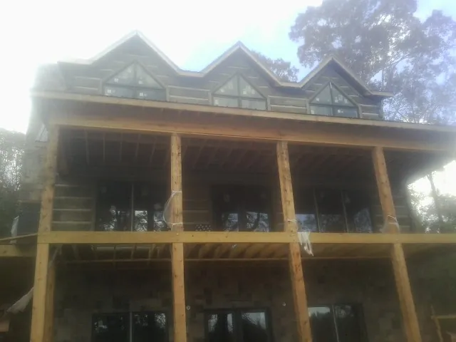 Dormers and porch framing on a large log home under construction — Roof Coating work by our crew in Bonaparte