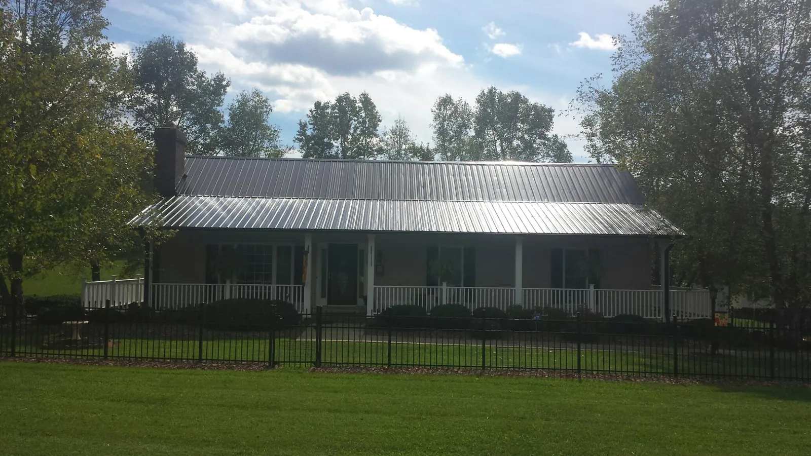 Gray metal roof on a brick ranch with a full width front porch — Gutter Guard Installation work by our crew in Bonaparte