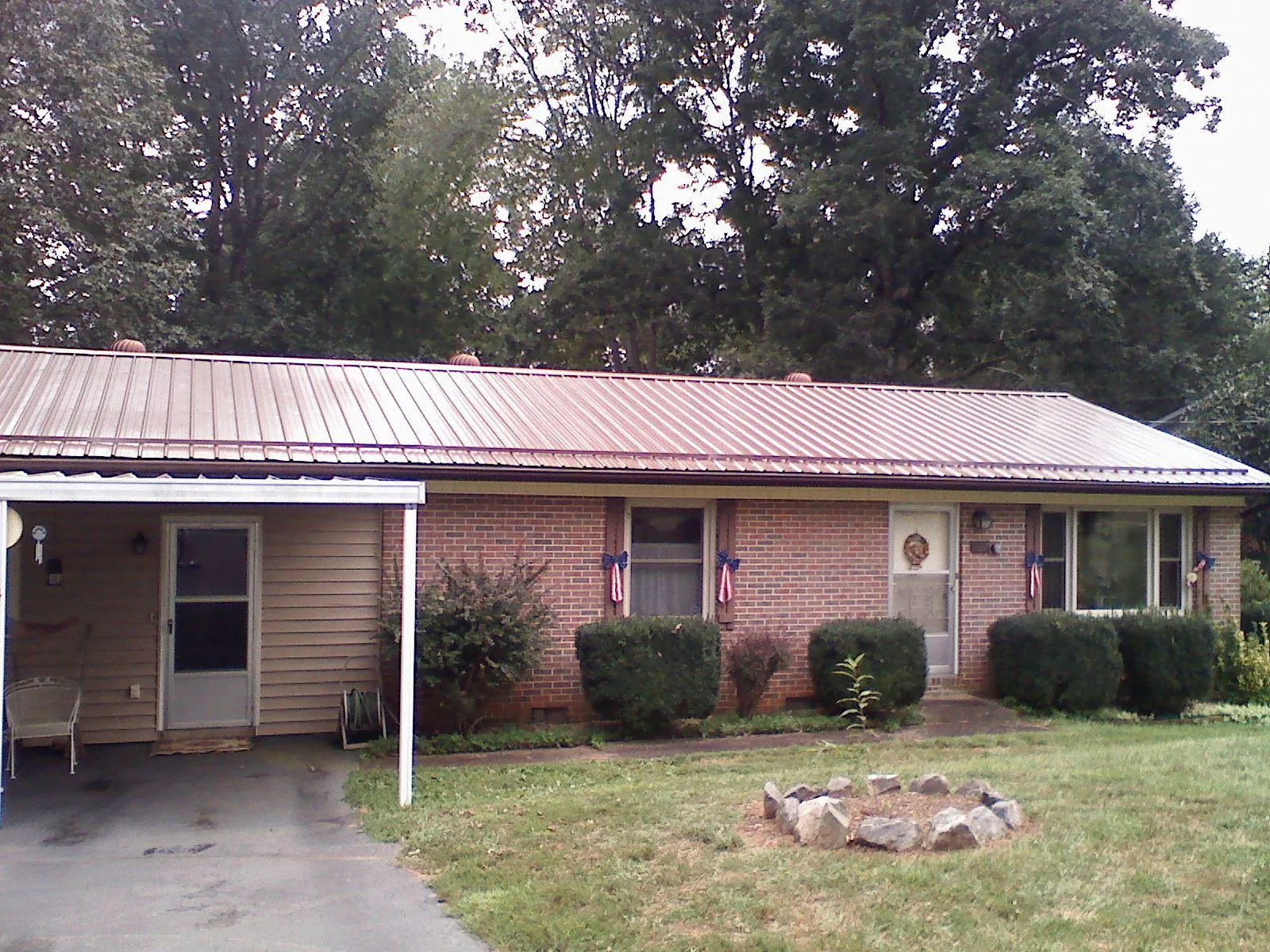 Bronze metal roof and carport on a brick ranch home — Roof Repair work by our crew in Bonaparte