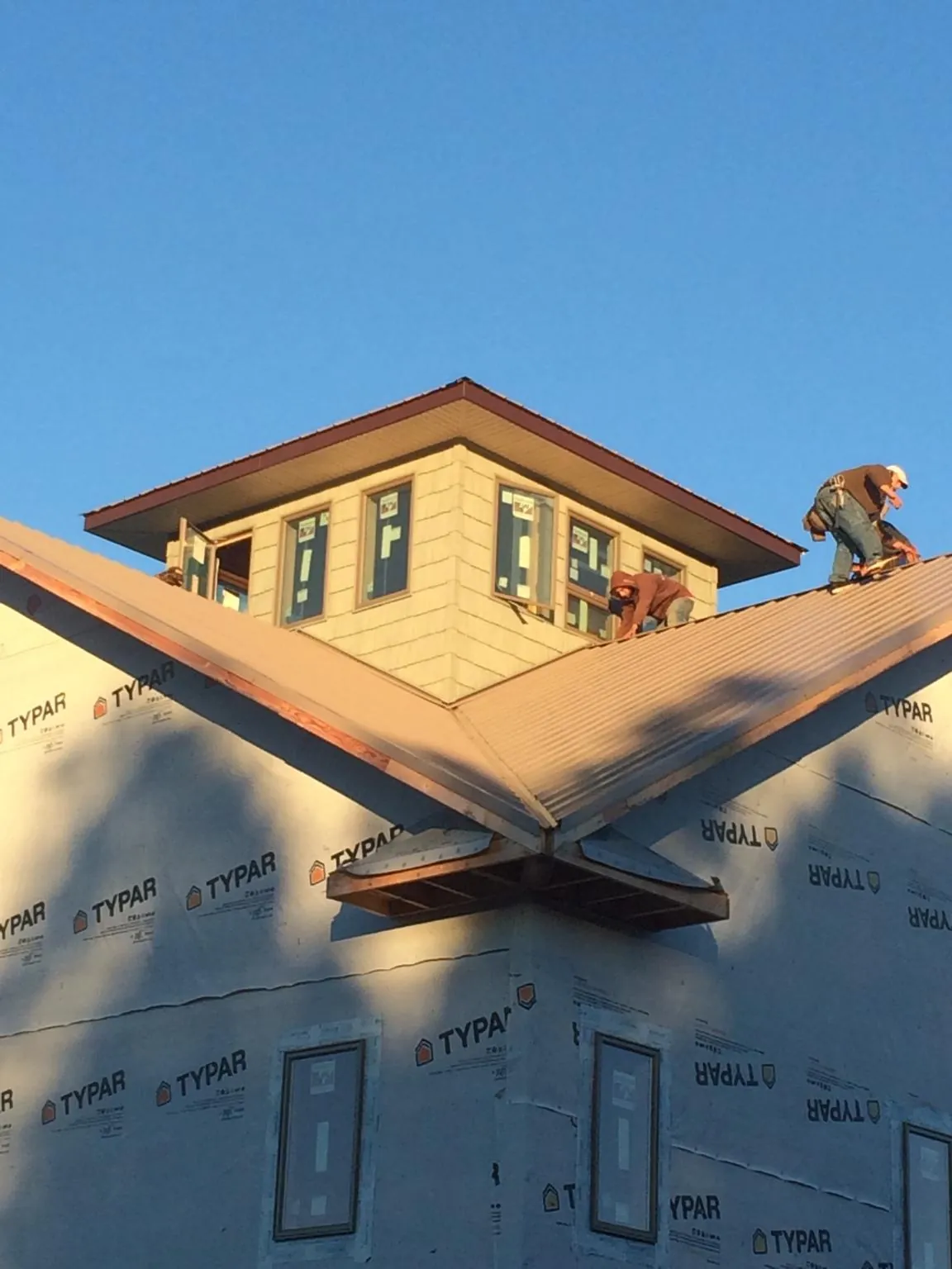 Roofers working around a rooftop cupola on a new metal roof at sunset — Roof Waterproofing in Bonaparte by Roofing Brothers